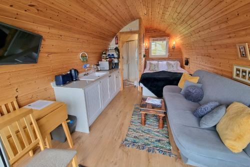 uma sala de estar com um sofá e um lavatório num quarto em Forester's Retreat Glamping - Cambrian Mountains View em Aberystwyth