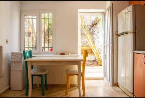 a kitchen with a table and two chairs and a refrigerator at Urla bir nefes taş ev in Urla