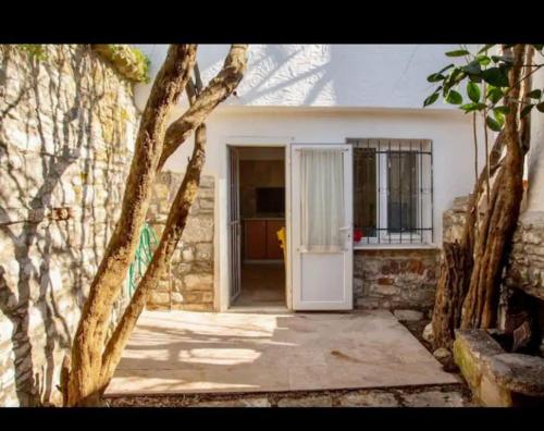 une maison avec une porte blanche et un mur en pierre dans l'établissement Urla bir nefes taş ev, à Urla