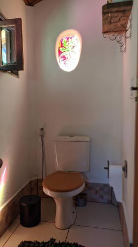a bathroom with a toilet with a window on the wall at Cecilia & Pretinho's House in Vale do Capao