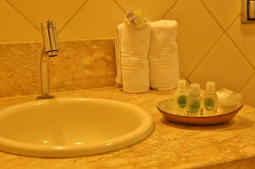 a sink in a bathroom with towels on a counter at Leão de Judá Charme Hotel in São Sebastião do Paraíso