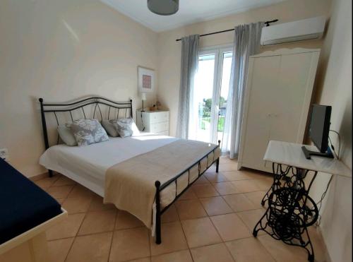 een slaapkamer met een bed, een televisie en een raam bij Sunny Coco mat villa in Katelios with a sea view in Kateliós