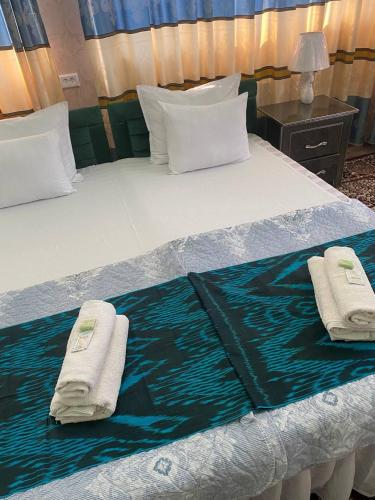 a bed with two towels on top of it at Hotel Guest House GOLDEN DEGREZ in Bukhara