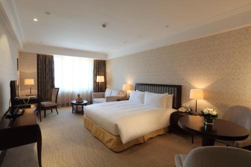 a hotel room with a bed and chairs and tables at Evergreen Laurel Hotel, Shanghai in Shanghai