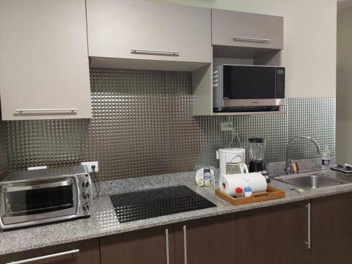 a kitchen counter with a microwave and a sink at Condo Playa Hermosa, Puntarenas in Muñeco
