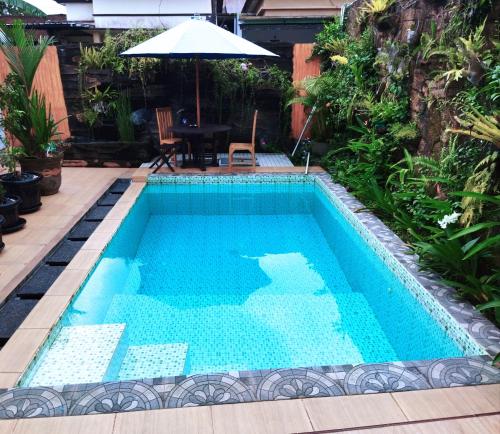 einen Pool mit einem Tisch und einem Sonnenschirm in der Unterkunft Villa Lim in Tabanan