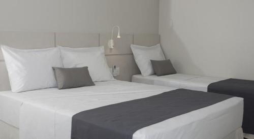 a bedroom with two white beds and a chair at Hotel Real Executive in Aparecida de Goiania