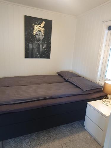 a bed in a bedroom with a picture on the wall at Small and cute apartment in city center in Tromsø