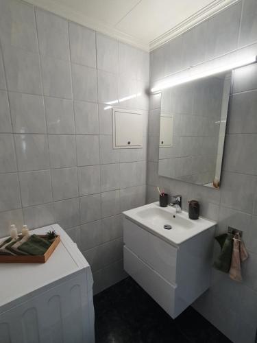 a white bathroom with a sink and a mirror at Small and cute apartment in city center in Tromsø