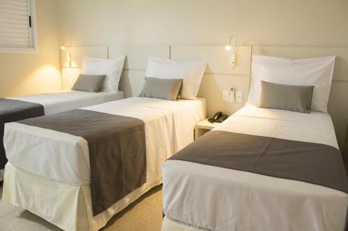 a hotel room with two beds with white sheets at Hotel Real Executive in Aparecida de Goiania