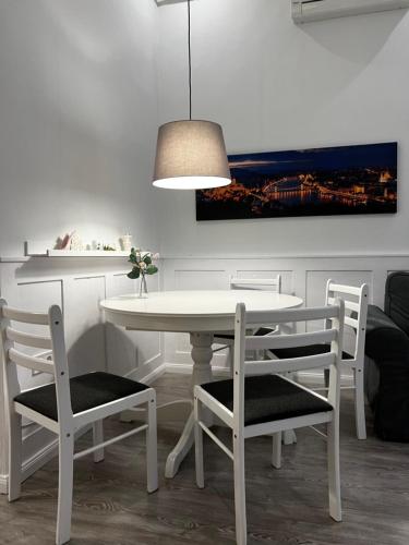 Pázmány Rest Apartman في بودابست: غرفة طعام مع طاولة بيضاء وكراسي