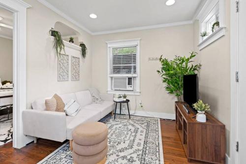 a living room with a white couch and a tv at Historic Heights Cozy Nook Apartment in Houston