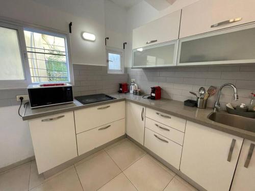 a kitchen with white cabinets and a sink at דירה גדולה יפיפיה קרובה לחוף הים in Tel Aviv