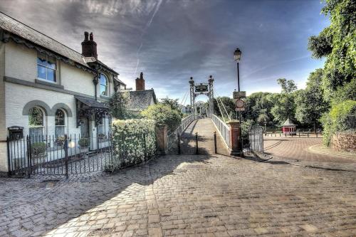 a gate to a building with a bridge in the background at Beautiful period cottage, exceptional riverside location in the heart of Chester in Chester