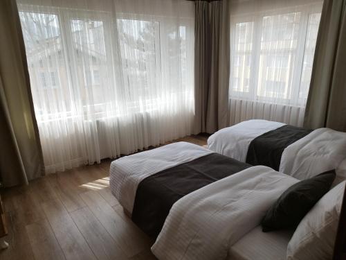 two beds in a hotel room with windows at Cozy Home Next to Green Mosque in Yıldırım