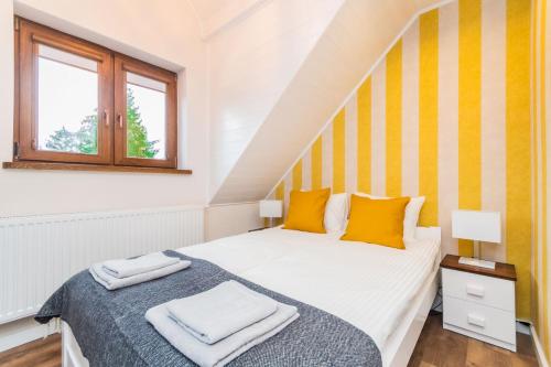 a bedroom with a bed with yellow and white stripes at Willa Green in Kąty Rybackie