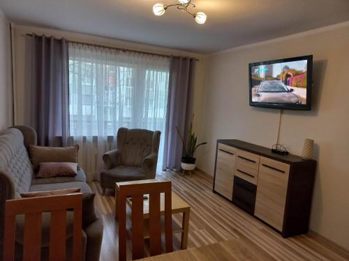 a living room with a couch and a tv on the wall at Apartament M-5 in Częstochowa