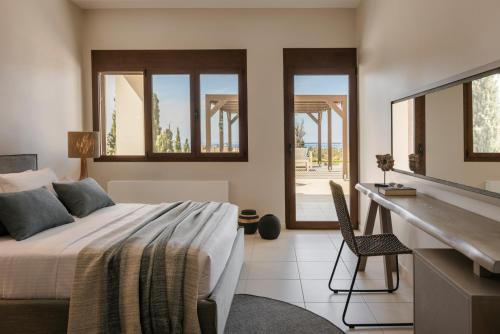 a bedroom with a bed and a desk and windows at Luxury Villa Karmaniolos Fiskardo Kefalonia in Fiskardho