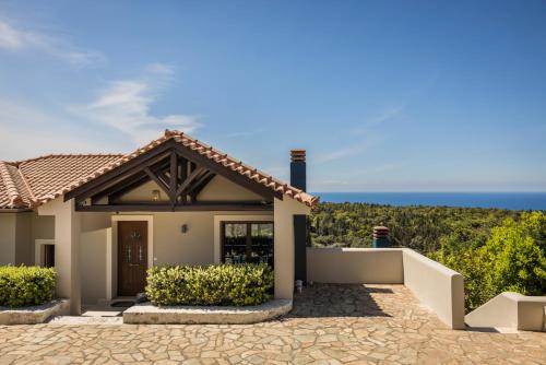 a house with the ocean in the background at Luxury Villa Karmaniolos Fiskardo Kefalonia in Fiskardho