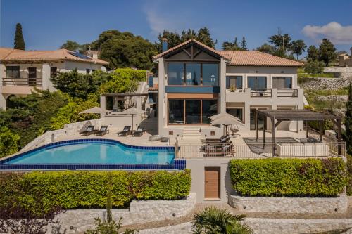 a home with a swimming pool and a house at Luxury Villa Karmaniolos Fiskardo Kefalonia in Fiskardo
