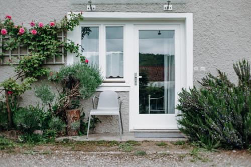 a white door with a chair in front of a house at Ferienwohnung am Sonnenberg in Busingen am Hochrhein