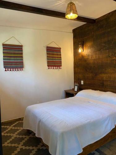 um quarto com uma cama branca e 2 janelas em Habitación Rancho Las Moras em San Mateo Río Hondo