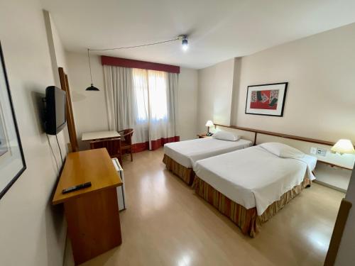 a hotel room with two beds and a television at César Park Hotel in Juiz de Fora