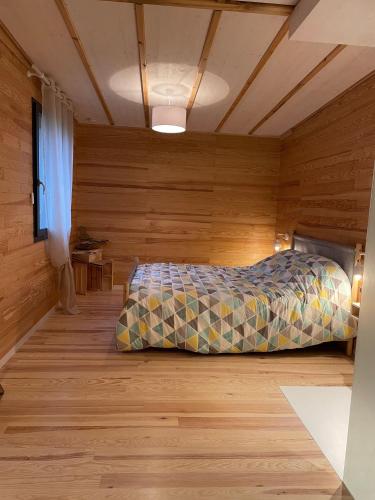 a bedroom with a bed in a room with wooden walls at L'écolodge de Laeti in Lunéville