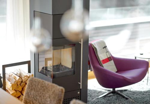 a living room with a purple chair and a fireplace at Design Villa M by Pferd auf Wolke in Gortipohl