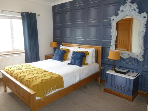 1 dormitorio con 1 cama con paredes azules y espejo en Gwynfryn Guest House, en Pembrokeshire