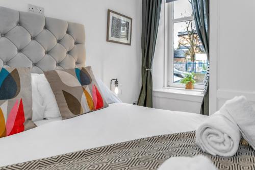 a bedroom with a white bed with a large headboard at Jamson Pl Apartment in Edinburgh