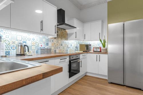 a kitchen with white cabinets and a stainless steel refrigerator at Jamson Pl Apartment in Edinburgh