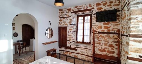 Habitación con pared de piedra y TV. en San Lorenzo Cottage - Παραδοσιακά Πέτρινα Δωμάτια, en Agios Lavredios
