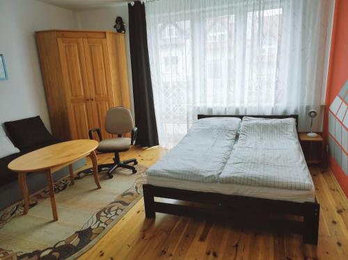 a bedroom with a bed and a table and a window at Pod 4 in Ustronie Morskie