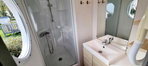 une salle de bain avec une douche, un lavabo et un miroir dans l'établissement Mobil-home 6 Personnes - Bretagne - Piscine - Plage, à Trégunc