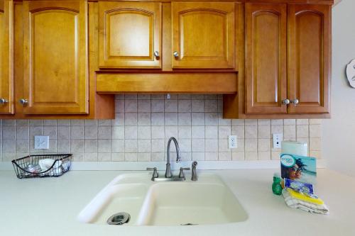 a kitchen counter with a sink and wooden cabinets at Seaside Beach & Racquet Club 5215 in Orange Beach