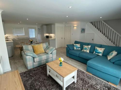 a living room with a blue couch and a table at Surf's Up! Atlantic Reach, Nr Newquay, Cornwall. Perfect base for holidays or work in Saint Columb Major