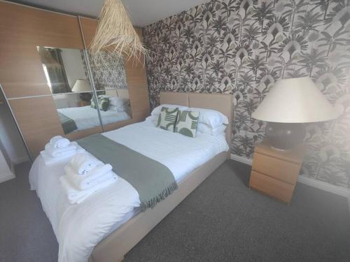 1 dormitorio con cama, lámpara y espejo en Shoreline Seaside Holiday Home Aberavon beach en Port Talbot