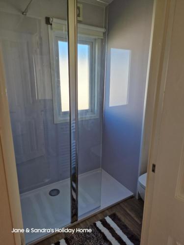 La salle de bains est pourvue d'une douche avec une porte en verre. dans l'établissement PRIVATELY OWNED Stunning Caravan Seawick Holiday Park St Osyth, à Jaywick Sands