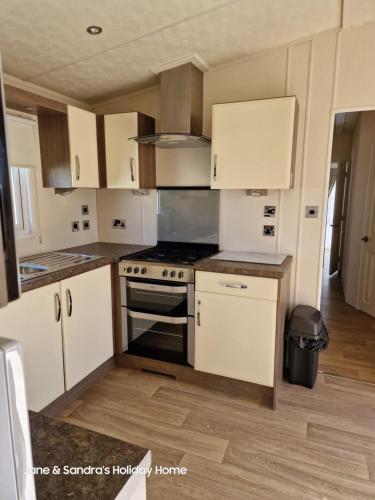 a kitchen with white cabinets and a stove top oven at PRIVATELY OWNED Stunning Caravan Seawick Holiday Park St Osyth in Jaywick Sands