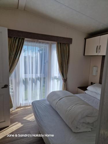 a bedroom with a bed and a large window at PRIVATELY OWNED Stunning Caravan Seawick Holiday Park St Osyth in Jaywick Sands