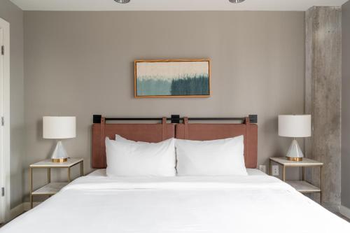 a bedroom with a large white bed with two lamps at Kasa Downtown Austin in Austin