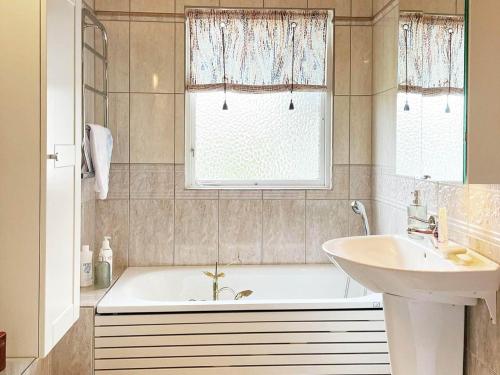 ein Bad mit einer Badewanne, einem Waschbecken und einem Fenster in der Unterkunft Holiday home SÖLVESBORG XII in Sölvesborg