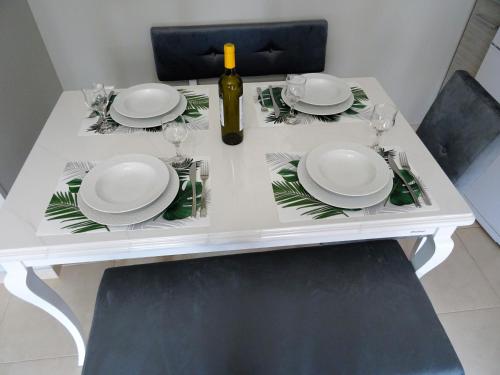 un tavolo bianco con piatti e una bottiglia di vino di Lefkada CP Residences a Città di Lefkada