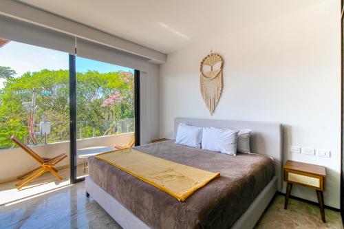 a bedroom with a bed and a large window at Menesse Tulum #204A Downtown in Tulum
