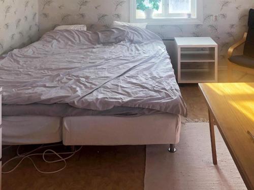 an unmade bed in a bedroom with a table at Holiday home ÖSTERSUND in Östersund