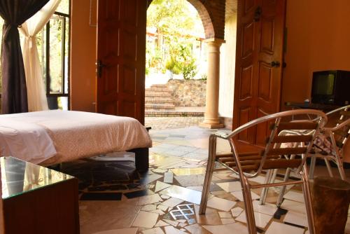 a bedroom with a bed and chairs in a room at Hotel Campestre Villa Los Duraznos in Paipa