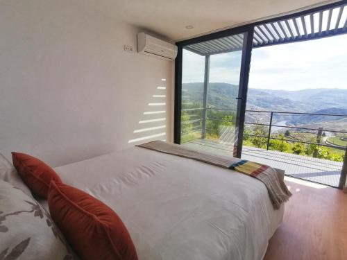 een slaapkamer met een bed en een groot raam bij Casa Miradouro in Mesão Frio