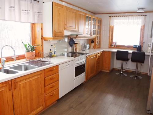 a kitchen with white appliances and wooden cabinets at Loghouse apartment in arctic wonderland! in Kvaløya