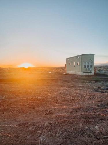 a small building in a field with the sunset in the background at Grand Canyon Hideaway Tiny home in Valle